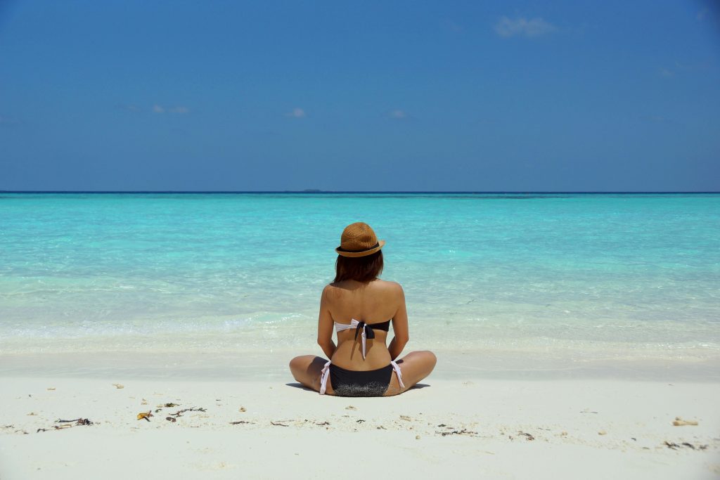 pexels-photo-67818-67818 Rear view of a woman in a bikini and hat relaxing on a pristine beach in Maldives.